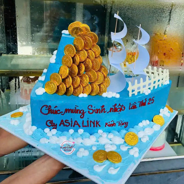 Bánh kem con thuyền thuận buồm xuôi gió trang trí cánh buồm trắng và đồng tiền vàng tượng trưng cho tài lộc, thành công.